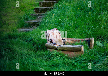 Abandoned sofa in London garden overgrown with grass Stock Photo