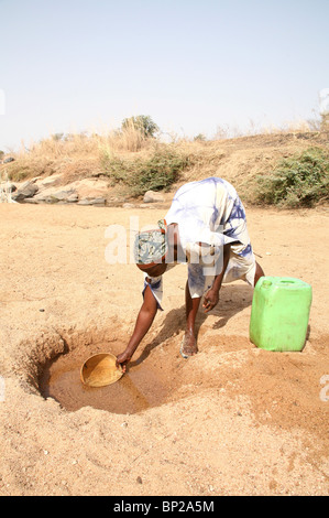 A woman collects water from a dry river bed in Northern Ghana, West Africa Stock Photo