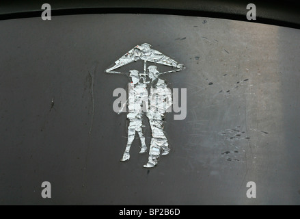 Graffiti on a grey metal wall in London, UK, of a man and woman walking underneath an umbrella Stock Photo