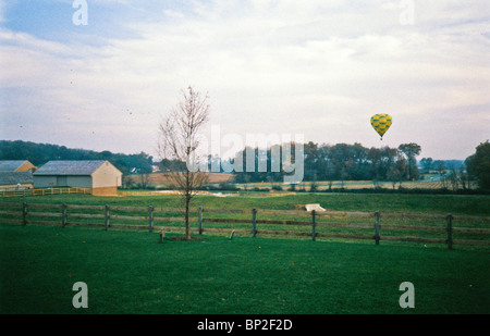Hot air balloon riders soar , float over Lancaster farm fields, early morning. Stock Photo