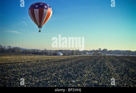 Hot air balloon riders soar , float over Lancaster farm fields, early morning. Stock Photo