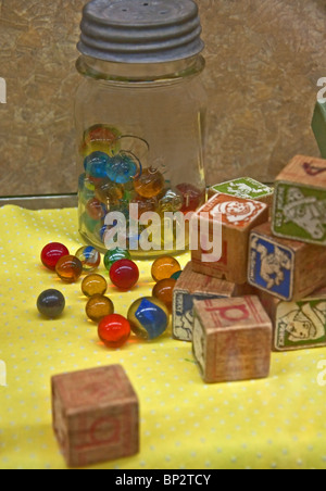 Antique still life depicts objects from a bygone era, vintage colorful marbles in an old mason jar with a metal lid, blocks. Stock Photo