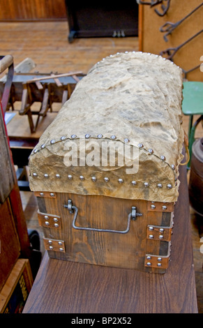 This vertical photo is of an old antique handmade saddle back trunk with other retro collectibles nearby. Stock Photo