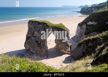 Young woman walks on deserted beach at the White Rocks between Portrush and Bushmills, Northern Ireland. Eroded limestone cliffs Stock Photo