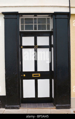 White and black painted wooden paneled front door no. 20 with brass knob letterbox and black surround of period town house in UK Stock Photo