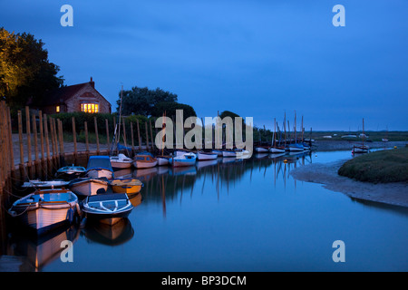 Blakeney quayside at dusk with boats moored up in channel, Norfolk, England Stock Photo