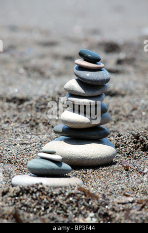 Balanced stones on beach sand. Vertical composition. Shallow DOF. Stock Photo