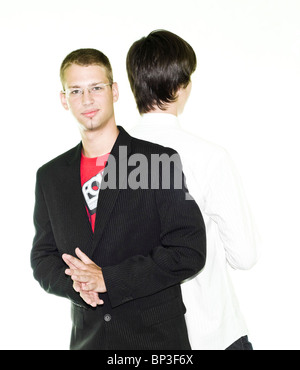 Two young businessmen leaning on each other, isolated on white background Stock Photo