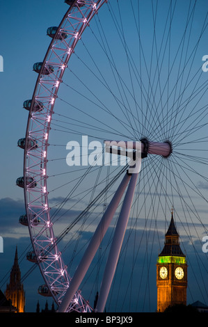The London Eye, or Millennium Wheel in front of the Palace of Westminster showing the clock tower that houses Big Ben at sunset. Stock Photo