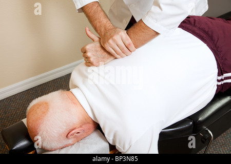 Closeup of chiropractors hands doing spinal adjustment on senior man.  Stock Photo