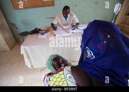 Paramedic treats a young mother and child at a feeding centre started by Christian Aid partner HEKS. Stock Photo