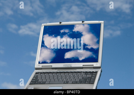 laptop computer with cloud images and clouds in background representing cloud computing Stock Photo