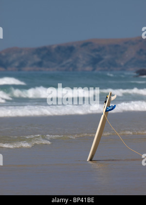 Surfboard upright in the sand, Watergate Bay, Cornwall, UK Stock Photo