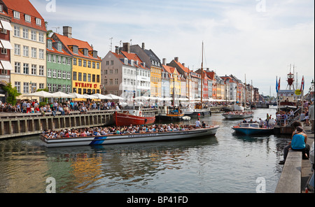 Nyhavn canal full of manoeuvring canal tour boats and crowded waterside restaurants on a very busy summer day Stock Photo