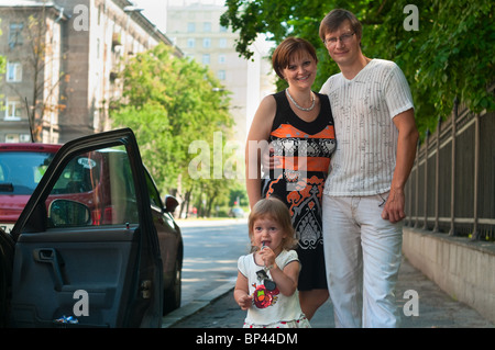 Happy parents near a new car and child here Stock Photo