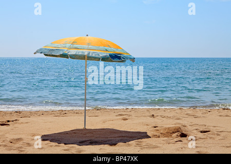 Lonely umbrella on the beach near the ocean on sunny day Stock Photo