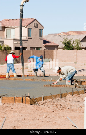 A crew of construction workers pour a concrete pad for a new house. Stock Photo