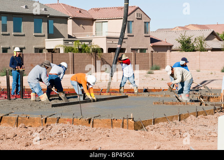 A crew of construction workers pour a concrete pad for a new house. Stock Photo