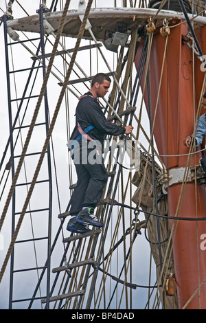 crewman on a square rigged sailing ship working high in the rigging. Stock Photo