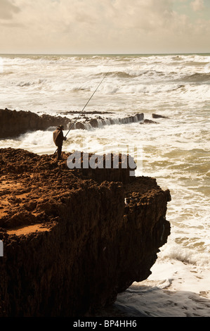 Plage Aglou with Fisherman on cliffs above the crashing Atlantic Ocean, near Tiznit, Morocco Stock Photo