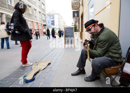 Busker playing guitar on Chmielna street, Warsaw Poland. Stock Photo