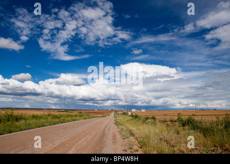 Picturesque scene of a farm along a dirt road in a vast rural landscape with cumulus cloud formations in southwest Colorado Stock Photo