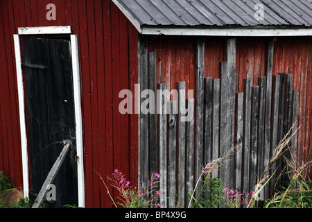 Traditional Nordic shed outhouse with repaired wood black door supported flaking old paint, Aland archipelago, Finland Stock Photo