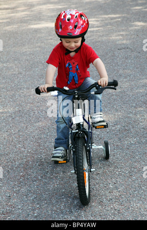 Little boy toddler riding his first bicycle with stabilisers MODEL RELEASED Stock Photo