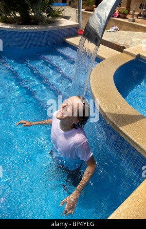 A  youth takes a shower in the swimming pool. Stock Photo