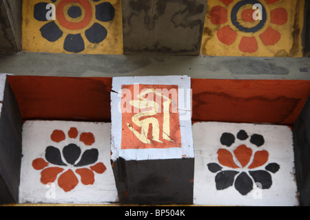 A roof feature with buddhist religious symbols and lettering on a wall of the Tashichho Dzong monastery in Thimpu, Bhutan. Stock Photo