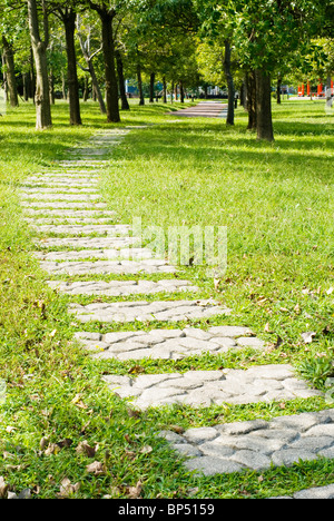 Stone walkway into woods in the park Stock Photo