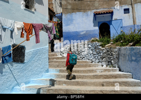 Moroccan Schoolboy Climbing Steps, Stairs or Stairway in the Old Town, Medina or Historic District of Chefchaouen, Morocco Stock Photo