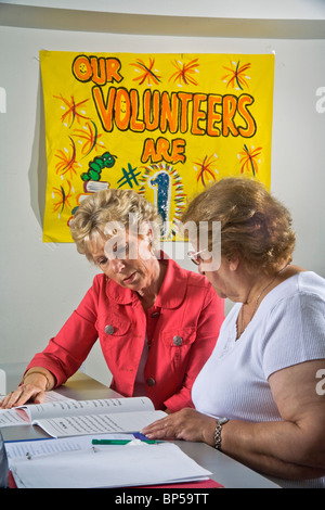 Using 'word card' components to form a complete word, a volunteer adult literacy teacher instructs an elderly Hispanic student. Stock Photo