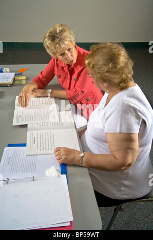 Using 'word card' components to form a complete word, a volunteer adult literacy teacher instructs an elderly Hispanic student. Stock Photo