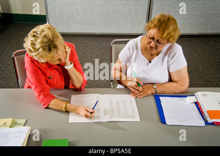 Using 'word card' components to form a complete word, a volunteer adult literacy teacher instructs an elderly Hispanic student. Stock Photo