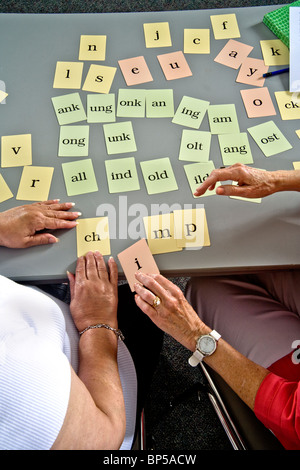 Using 'word card' components to form a complete word, a volunteer adult literacy teacher an Hispanic elderly student to read. Stock Photo