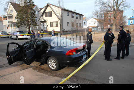 New Haven,CT USA--New Haven Police Officers stand near a car possibly used in a double shooting. They are shown at 44 Elliot Street where the suspects bailed out of the car. Stock Photo