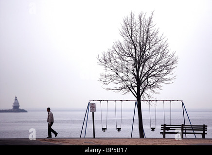 A man walks along an empty beach in the winter in New Haven Connecticut USA Stock Photo