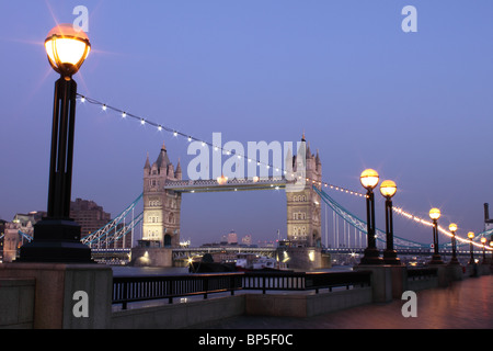 Tower Bridge at dusk from the South bank, with embankment lights in foreground and lights on bridge, London, England, UK Stock Photo