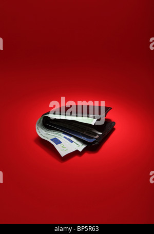 A black leather wallet with money on a bright red background, currency is 300 Euros Stock Photo