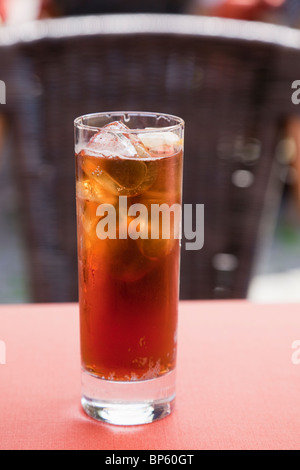 Europe. Full glass of iced tea with ice cubes and a slice of lemon on a table in a cafe Stock Photo