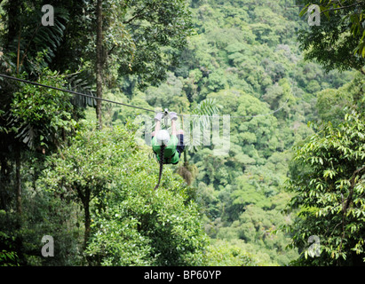 Girl riding a zipline above the rainforest canopy, La Fortuna, Costa Rica Stock Photo