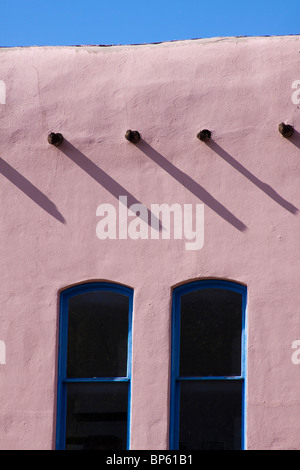 Vigas casting shadows over two windows of a building in the Pueblo revival style of architecture in Santa Fe, New Mexico Stock Photo