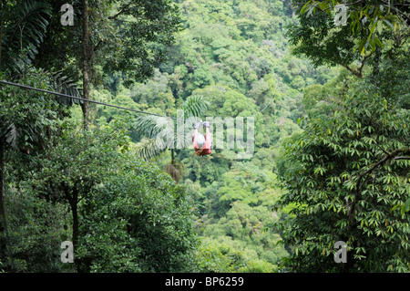 Girl riding a zipline above the rainforest canopy, La Fortuna, Costa Rica Stock Photo