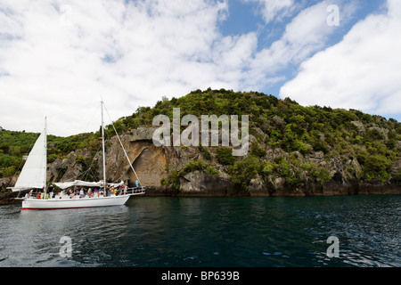 A tourist yacht at the mine bay rock carvings on Lake Taupo, New Zealand Stock Photo