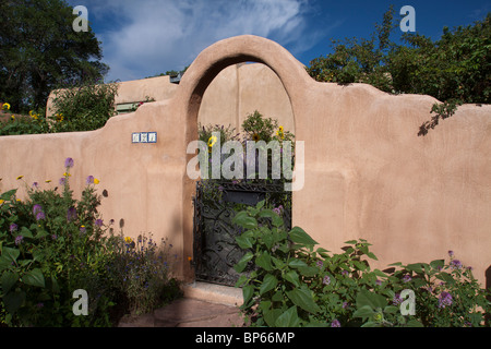 House with adobe low wall with arched front gate in Pueblo revival style  architecture of the Southwest in Santa Fe, New Mexico Stock Photo