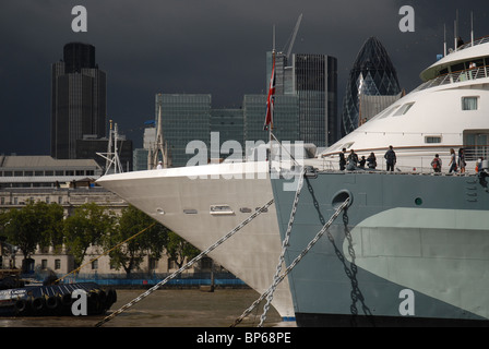Cruise liner Silver Cloud moored next to HMS Belfast on the River Thames with The Natwest Tower and Gherkin in the background Stock Photo