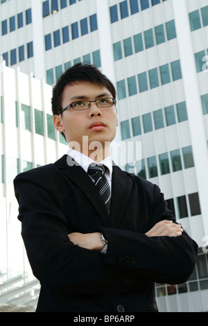 A young Asian businessman standing in front of an office building Stock Photo