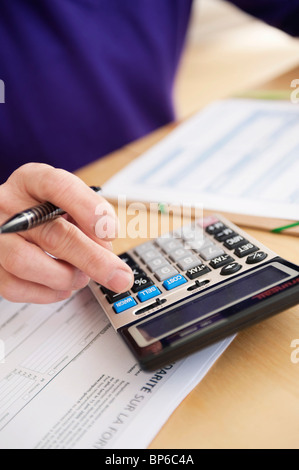 Man using calculator and filling his tax form Stock Photo