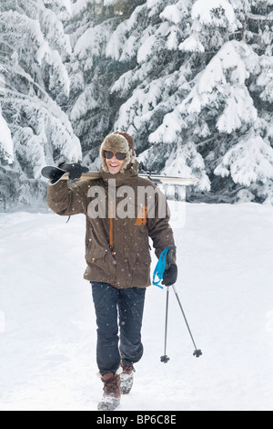 Young man carrying skis on shoulders Stock Photo